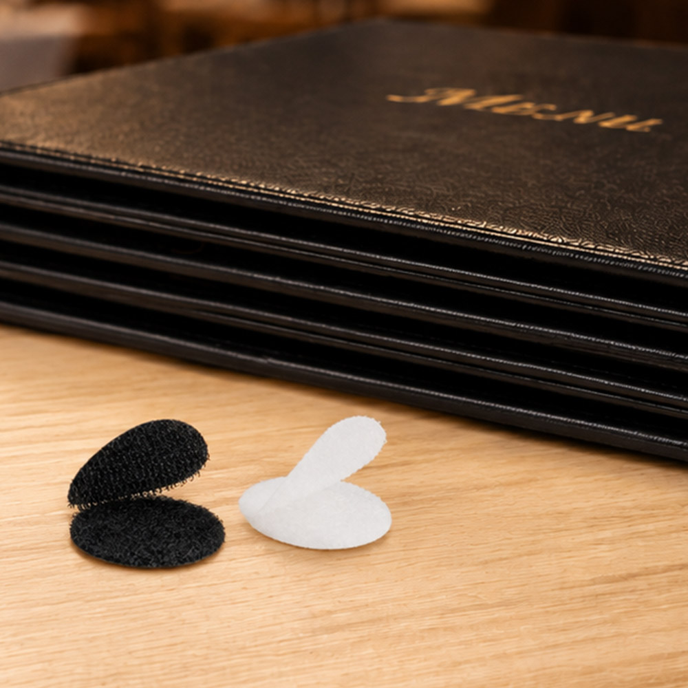 Weiße und schwarze Klettpunkte liegen vor einem Stapel Speisekarte auf einem Tisch im Restaurant